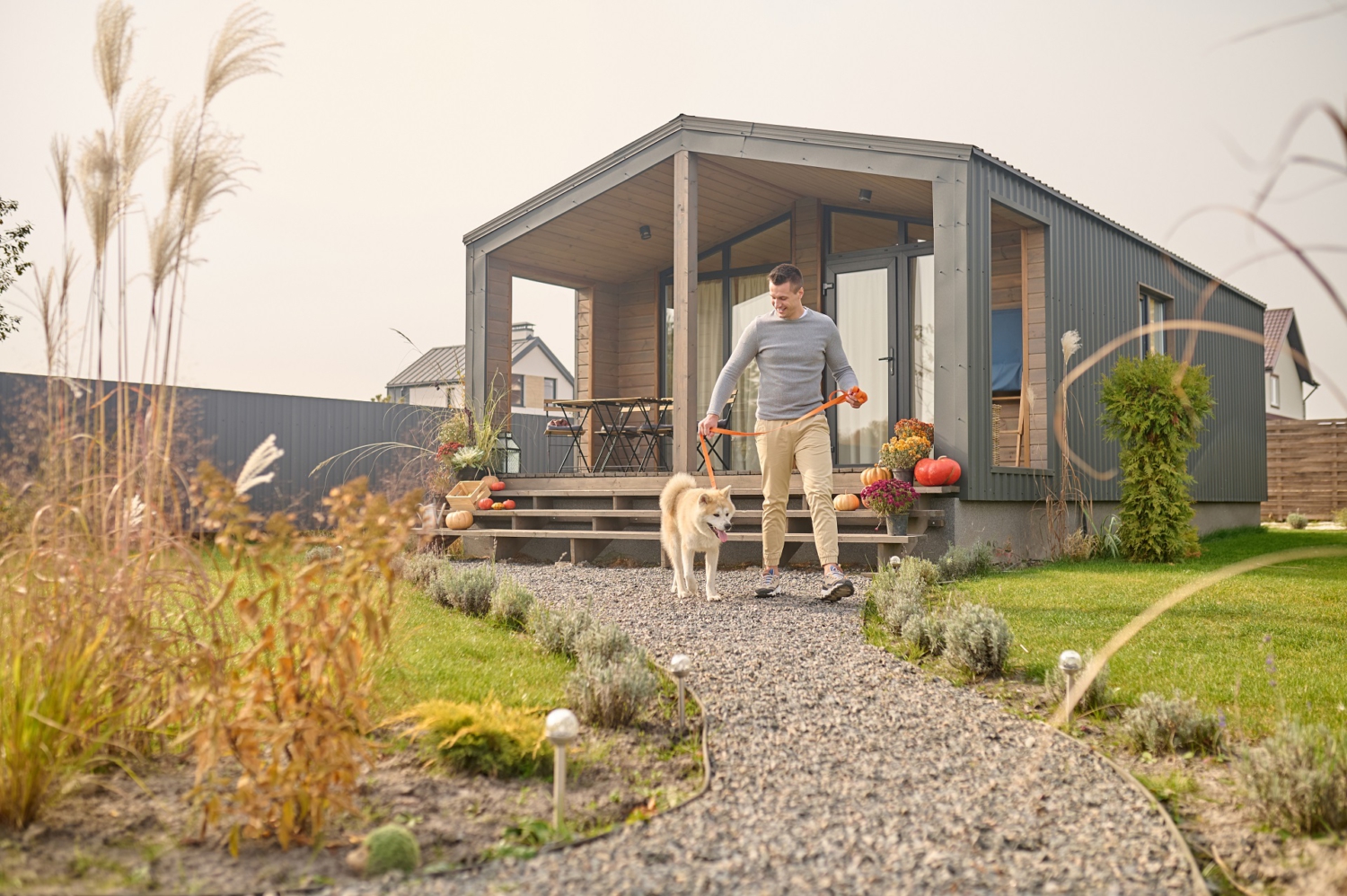 Ein Mann verlässt mit seinem weißen Hund das Haus über den Garten. Ein Mann verlässt mit seinem weißen Hund das Haus über den Garten.