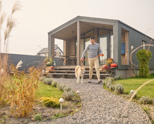 Ein Mann verlässt mit seinem weißen Hund das Haus über den Garten. Ein Mann verlässt mit seinem weißen Hund das Haus über den Garten.