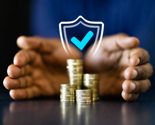 Zwei Hände umschließen einen Stapel Münzen. Darüber ist ein Schild mit einem blauen Hacken projiziert, dass die Sicherheit des Geldes symbolisiert.