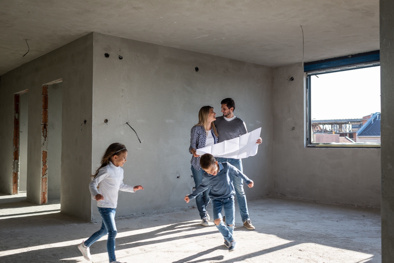 In der Mitte steht ein Pärchen in einem Rohbau. Es fehlen noch Fenster und Türen. Um sie herum rennen zwei Kinder, ein Junge und ein Mädchen. Die Eltern halten einen Plan in der Hand und lächeln sich an.