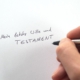 Hand schreibt „Mein letzter Wille und Testament“ auf ein Blatt Papier